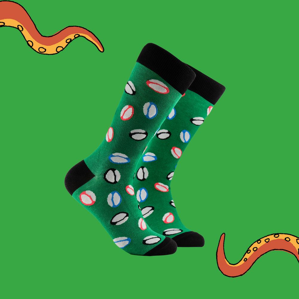 A pair of socks depicting rugby balls. Green legs, black cuff, heel and toe.