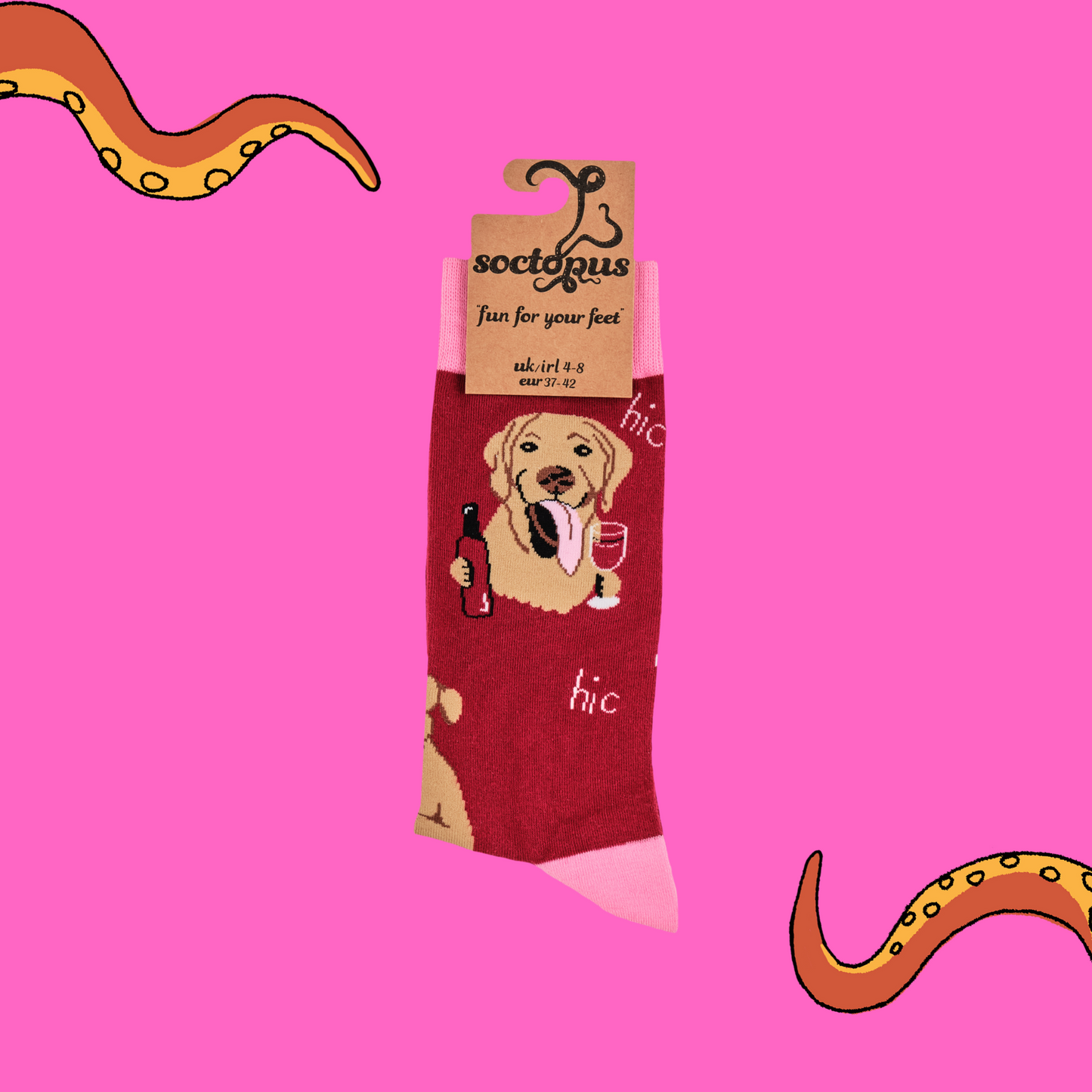A pair of socks depicting labs drinking wine. Red legs, light pink cuff, heel and toe. In Soctopus Packaging.