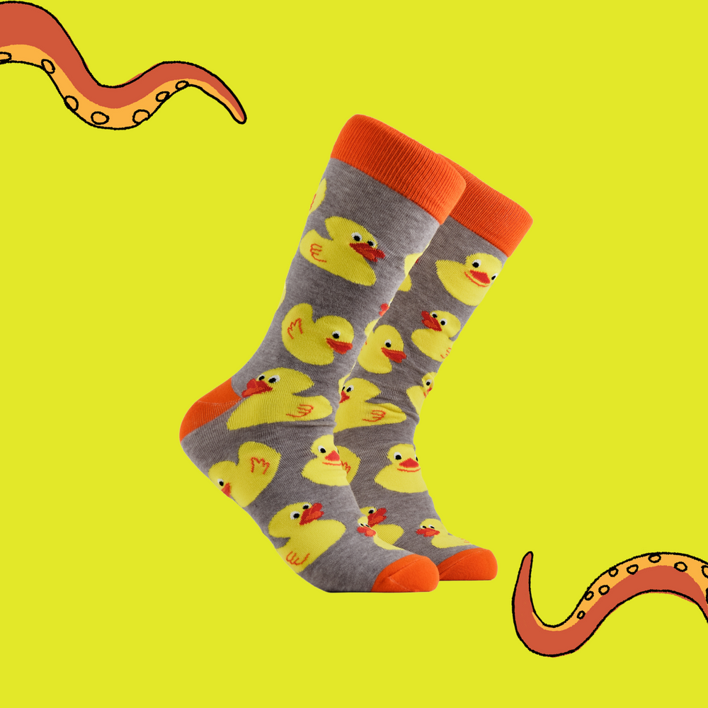 A pair of socks depicting rubber ducks. Grey legs, orange cuff, heel and toe.