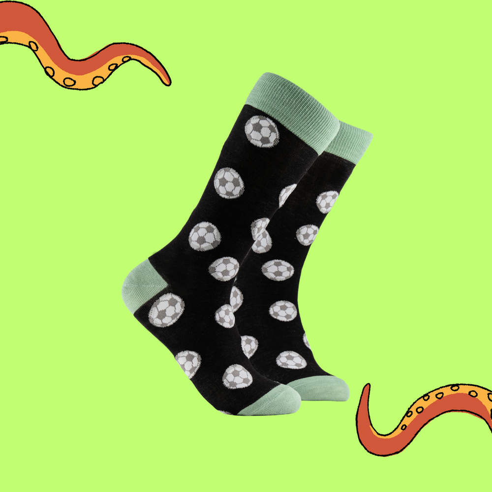A pair of socks depicting footballs. Black legs, light green cuff, heel and toe.