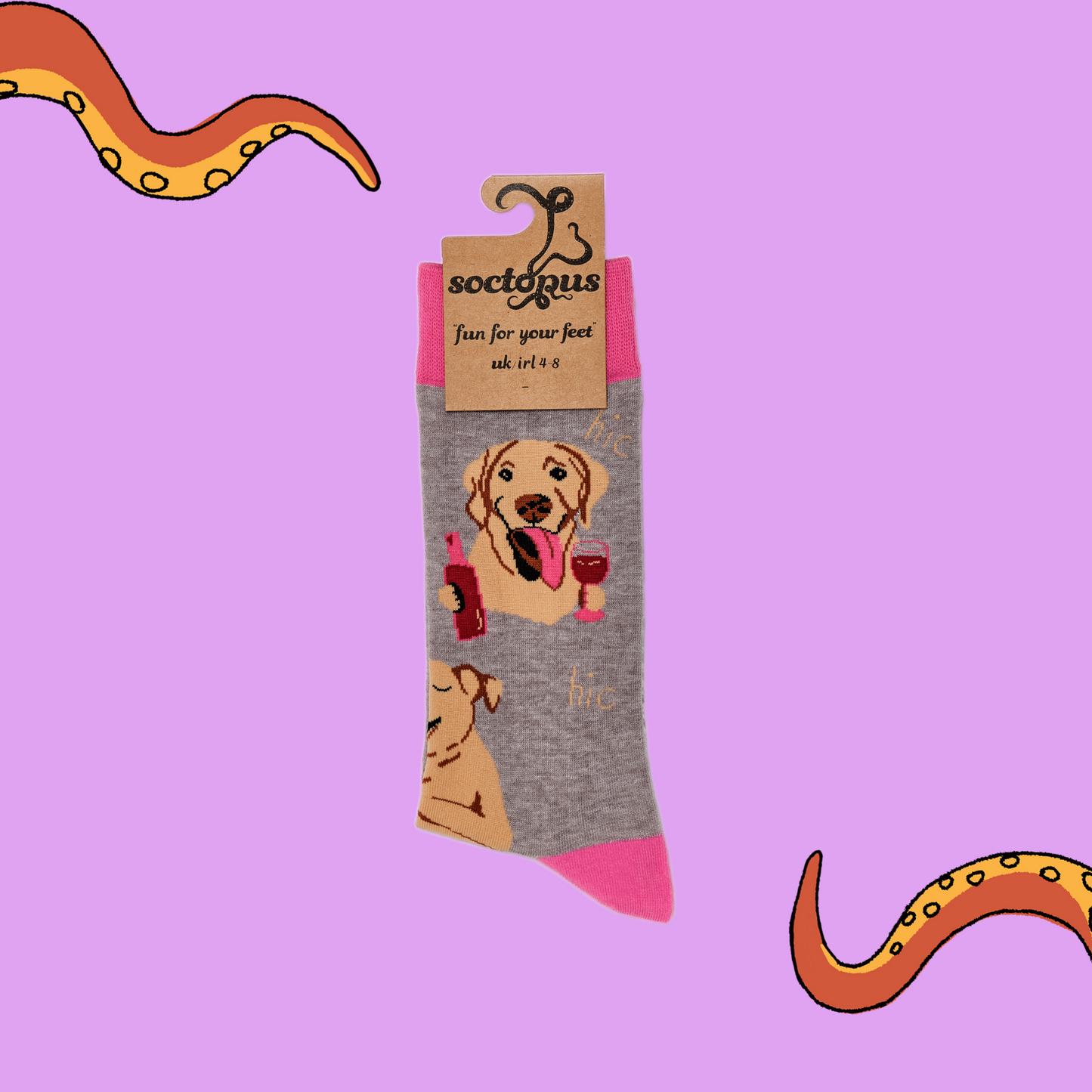 A pair of socks depicting labs drinking wine. Grey legs, light pink cuff, heel and toe. In Soctopus Packaging.