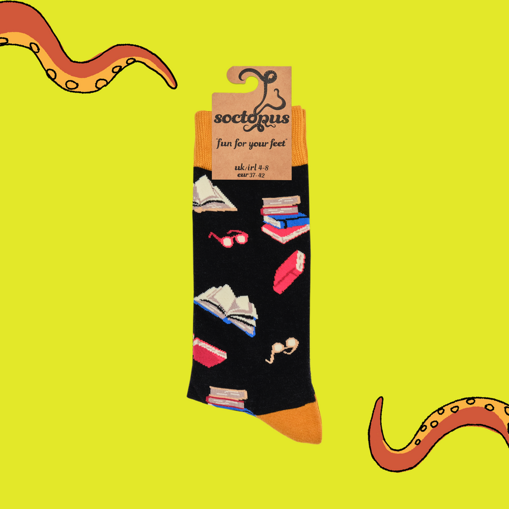 
                  
                    A pair of socks depicting books and reading glasses. Black legs, yellow cuff, heel and toe. In Soctopus Packaging.
                  
                