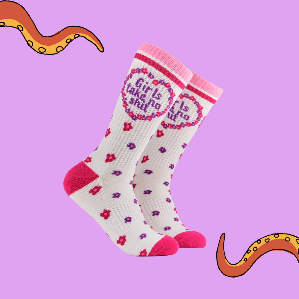 A pair of socks depicting the words "Girls Take No Shit". White legs, pink cuff, heel and toe.
