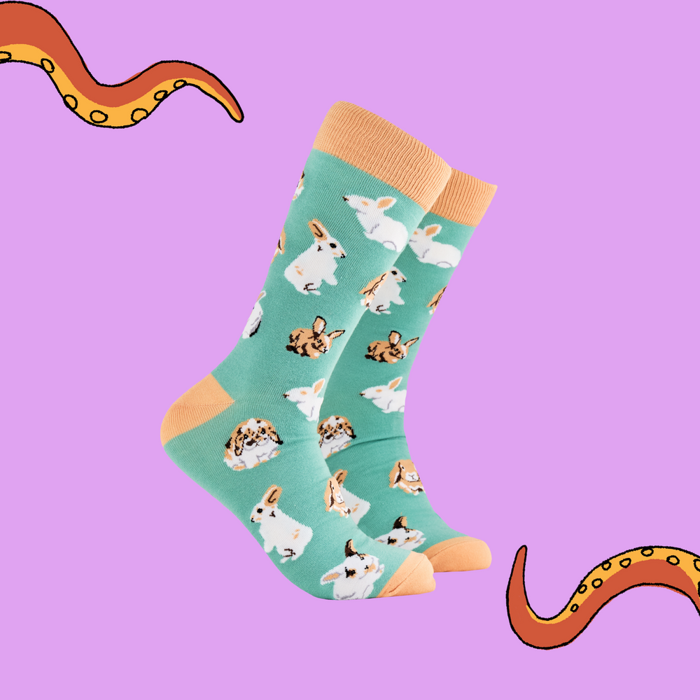 A pair of socks depicting rabbits playing. Green legs, brown cuff, heel and toe.