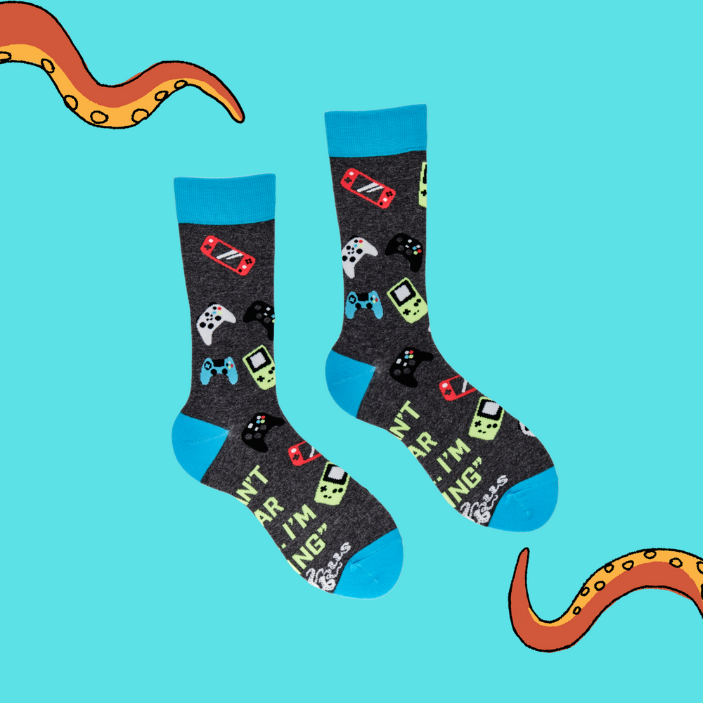 
                  
                    A pair of socks depicting game controllers and consoles. Grey legs, blue cuff, heel and toe.
                  
                