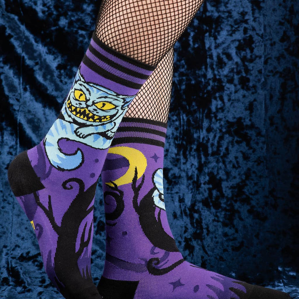 
                      
                        A model wearing a pair of socks featuring the cheshire cat. Purple legs, black heel, cuff and toe. 
                      
                    