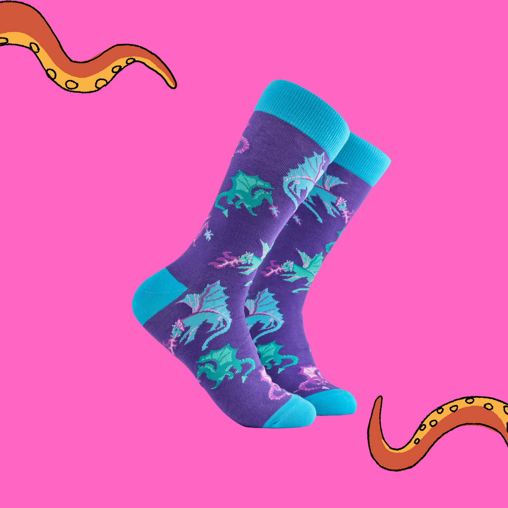A pair of socks depicting fire breathing dragons. Purple legs, turquoise cuff, heel and toe.