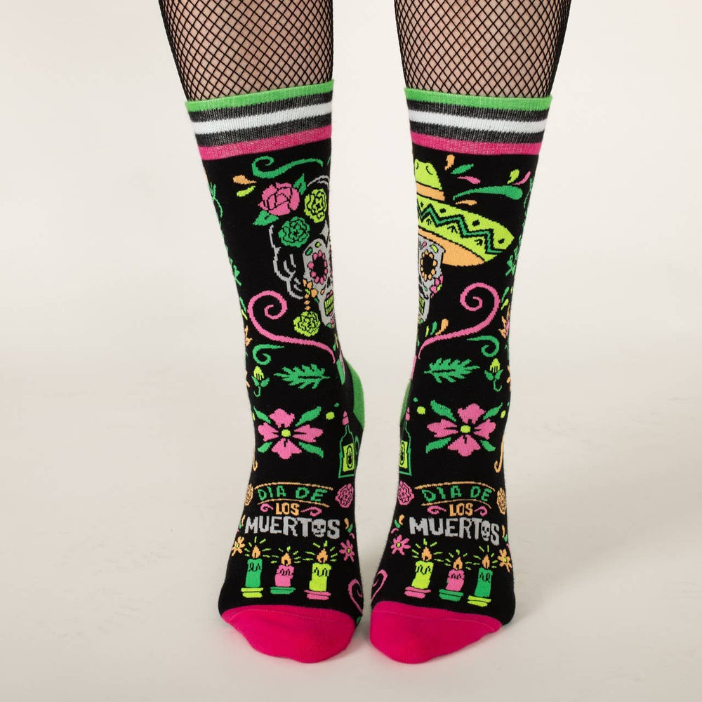 
                      
                        A model wearing a pair of socks with a day of the dead motif. Black legs, pink and green heel, toe and cuff. 
                      
                    