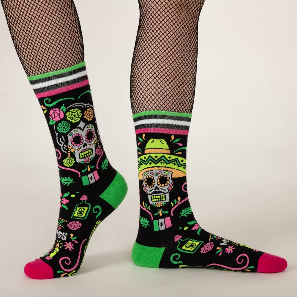 
                      
                        A model wearing a pair of socks with a day of the dead motif. Black legs, pink and green heel, toe and cuff. 
                      
                    