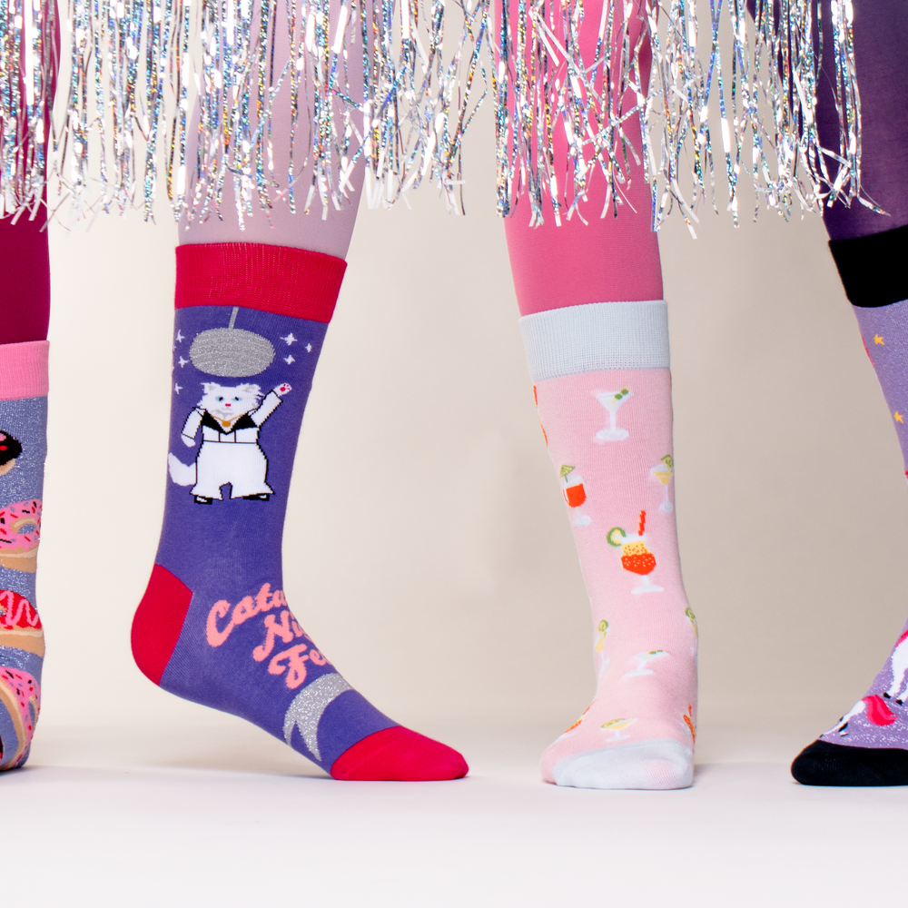 2 people wearing odd socks with a glitter curtain in the foreground.  