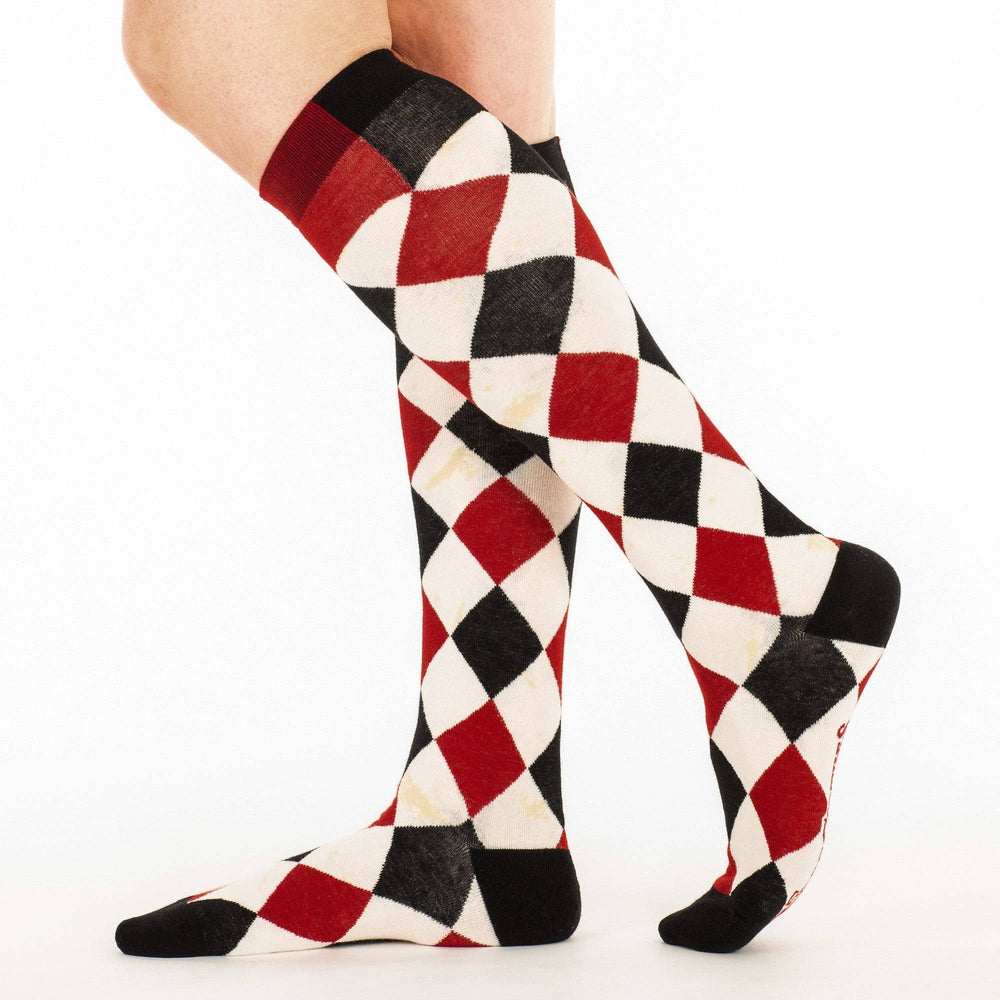 
                      
                        A model wearing a pair of knee high socks with a harlequin pattern. Black, white and red. 
                      
                    