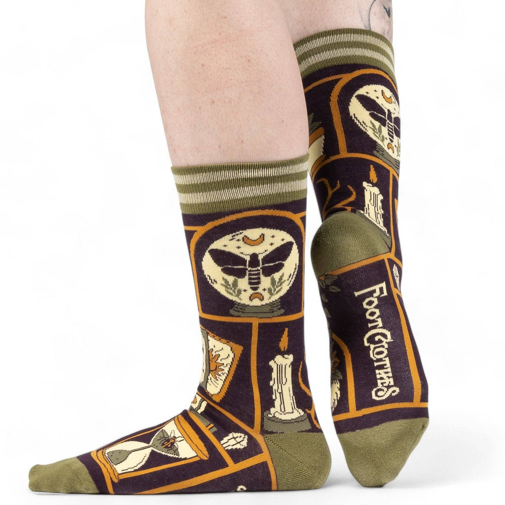 
                      
                        A model wearing a pair of socks depicting a collection of odd objects. Brown legs, green, heel, toe and cuff. 
                      
                    