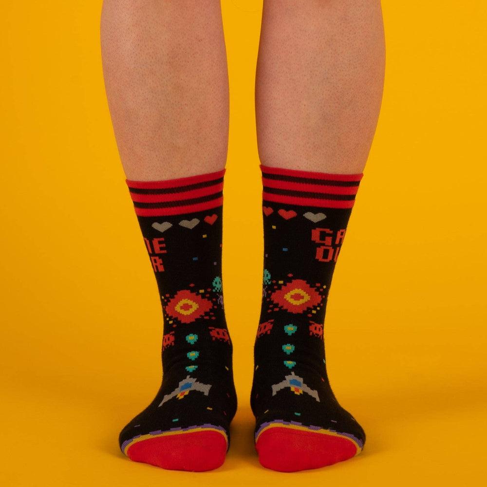 
                      
                        A model wearing a pair of socks featuring space invaders and game over. Black legs, red heel, toe and cuff. 
                      
                    