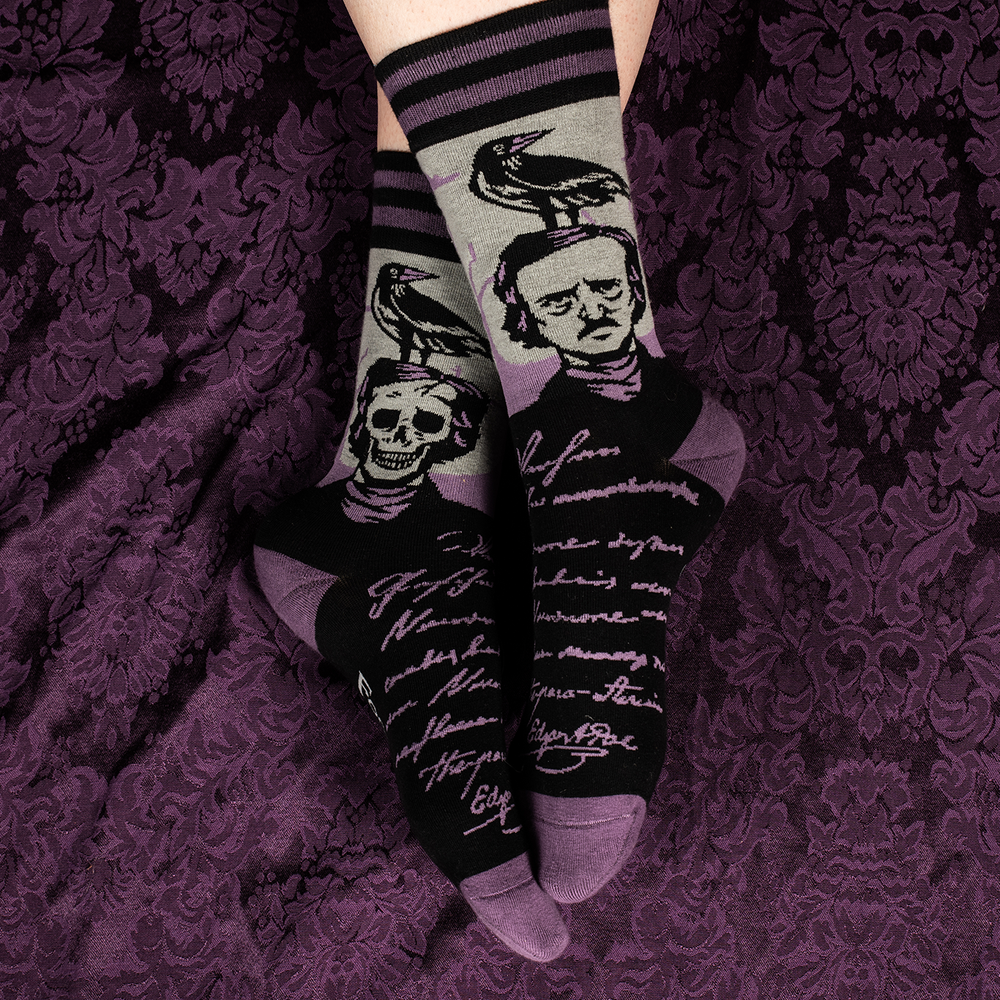 
                      
                        A pair of socks depicting a skeleton Edgar Allan Poe with a raven. Purple toes, heel and cuff. 
                      
                    