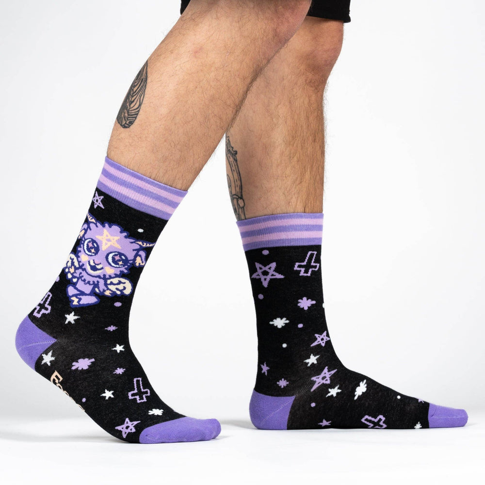 A model wearing a pair of socks depicting a baby version of the dark lord Baphomet. Purple toe, heel and cuff. 