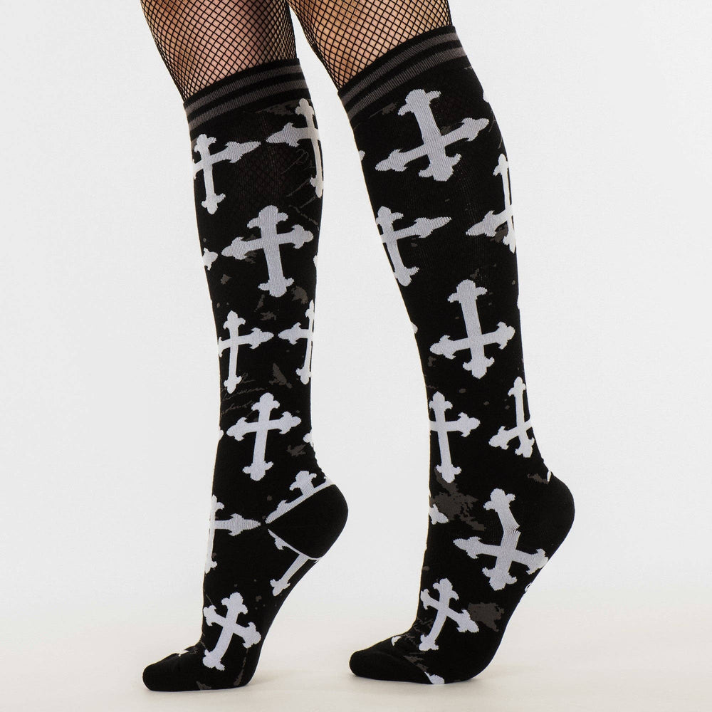 
                      
                        Model wearing a pair of knee high socks with a gothic cross pattern. Black and white. 
                      
                    