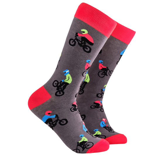 BMX Socks. A pair of socks depicting people riding BMX bikes. Grey legs, red cuff, heel and toe.