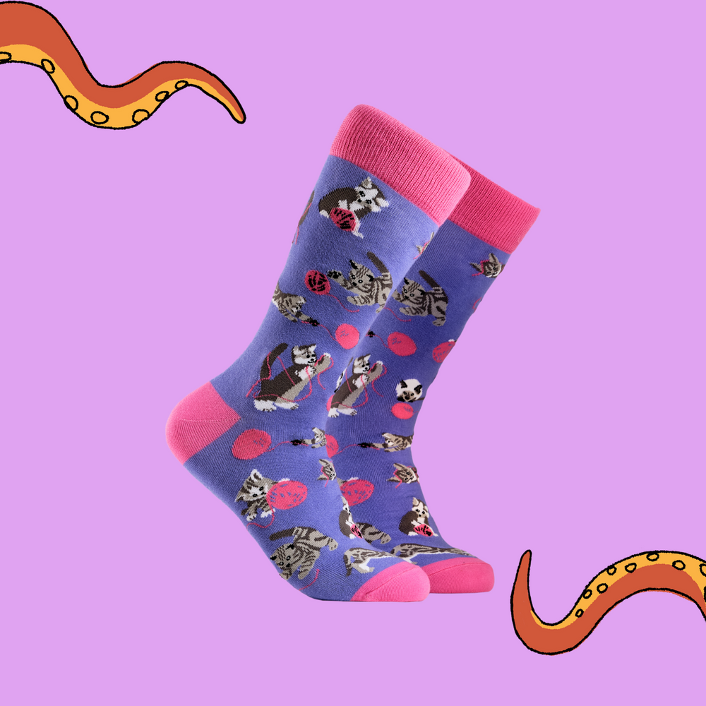 
                      
                        A pair of socks depicting cats playing with wool. Purple legs, pink cuff, heel and toe.
                      
                    