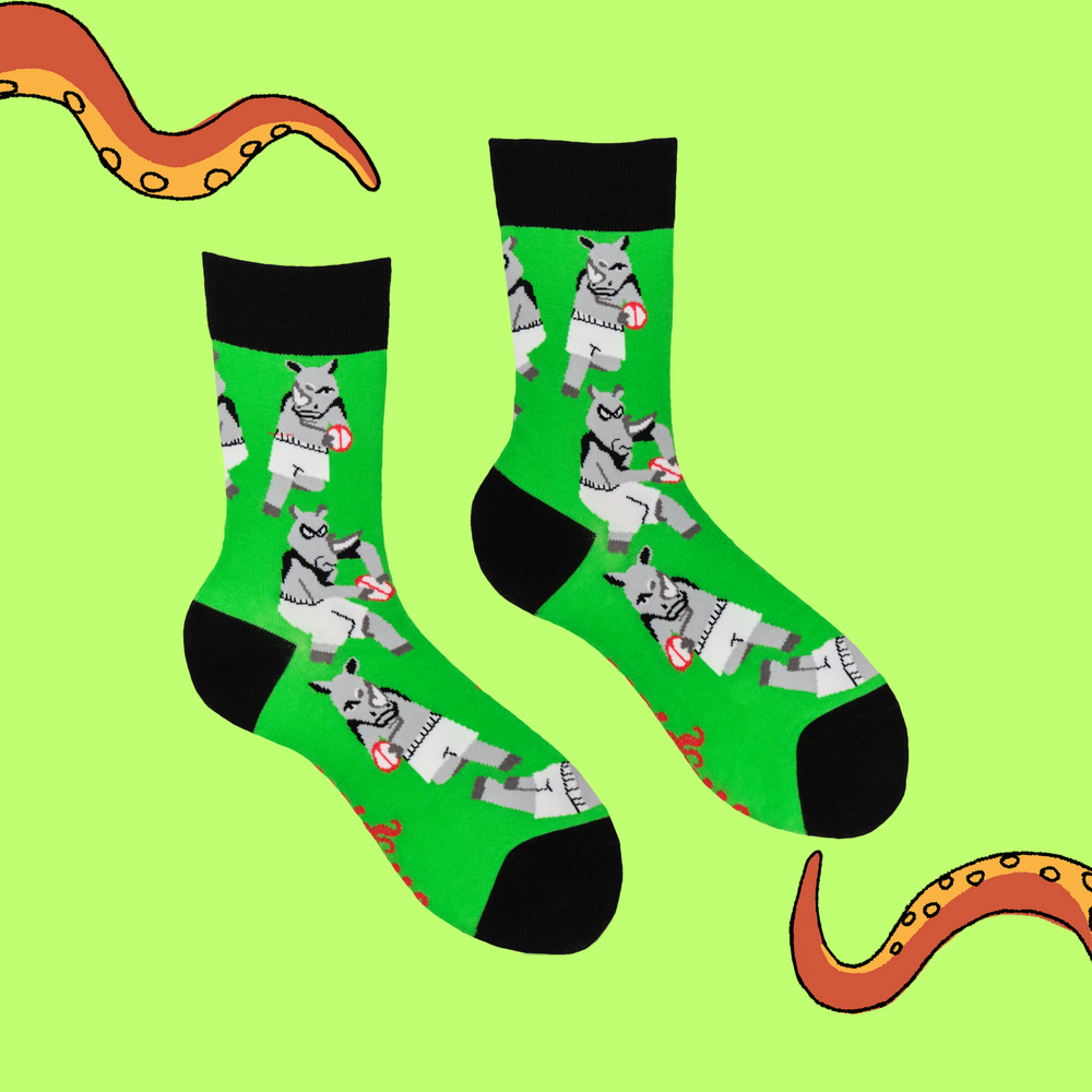 
                      
                        A pair of socks featuring rhinos playing rugby. Green legs, black heel, toe and cuff. 
                      
                    