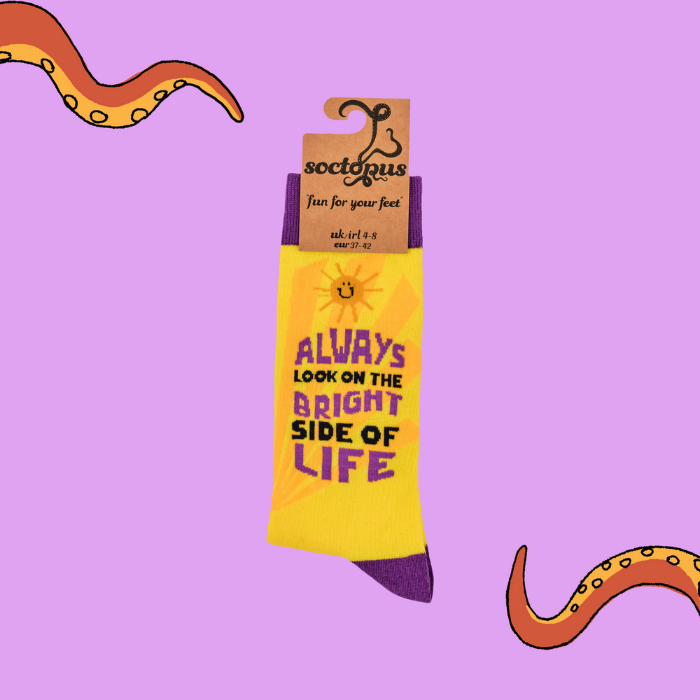 
                      
                        A pair of socks with the slogan 'Always look on the bright side of life'. Bright yellow legs, purple toe, cuff and heel. 
                      
                    