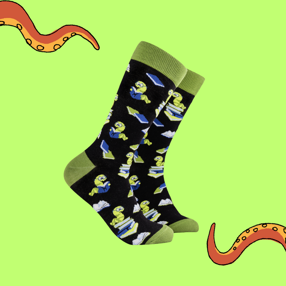 A pair of socks depicting worms reading books. Black legs, green cuff, heel and toe.