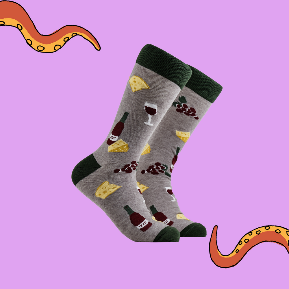 A pair of socks depicting wine, cheese and grapes. Grey legs, green cuff, heel and toe.