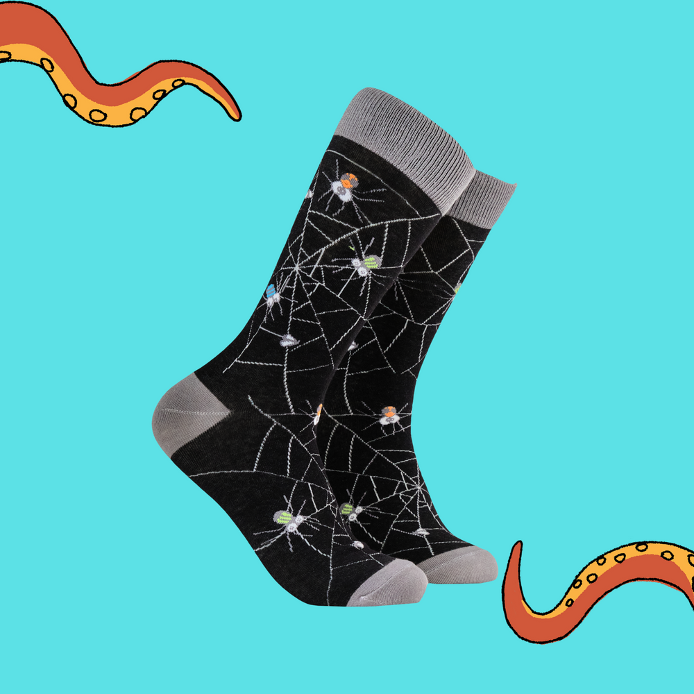 A pair of socks with googly eyed spiders. Black legs, grey heel, toe and cuff. 