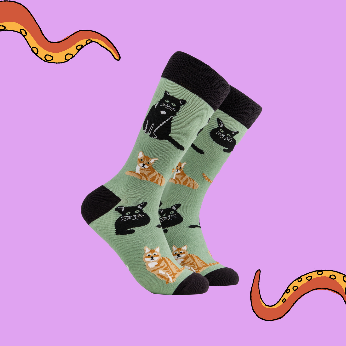 A pair of socks depicting cats. Green legs, black cuff, heel and toe.