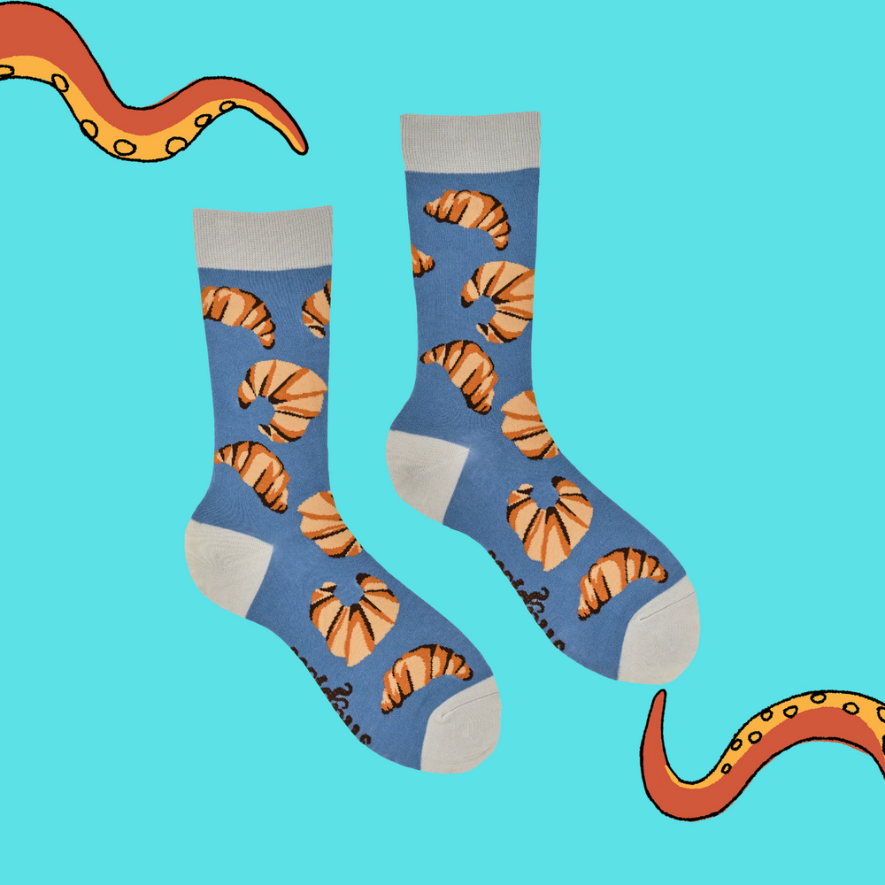 
                      
                        A pair of socks with a croissant motif. Blue legs, grey heel, toe and cuff. 
                      
                    