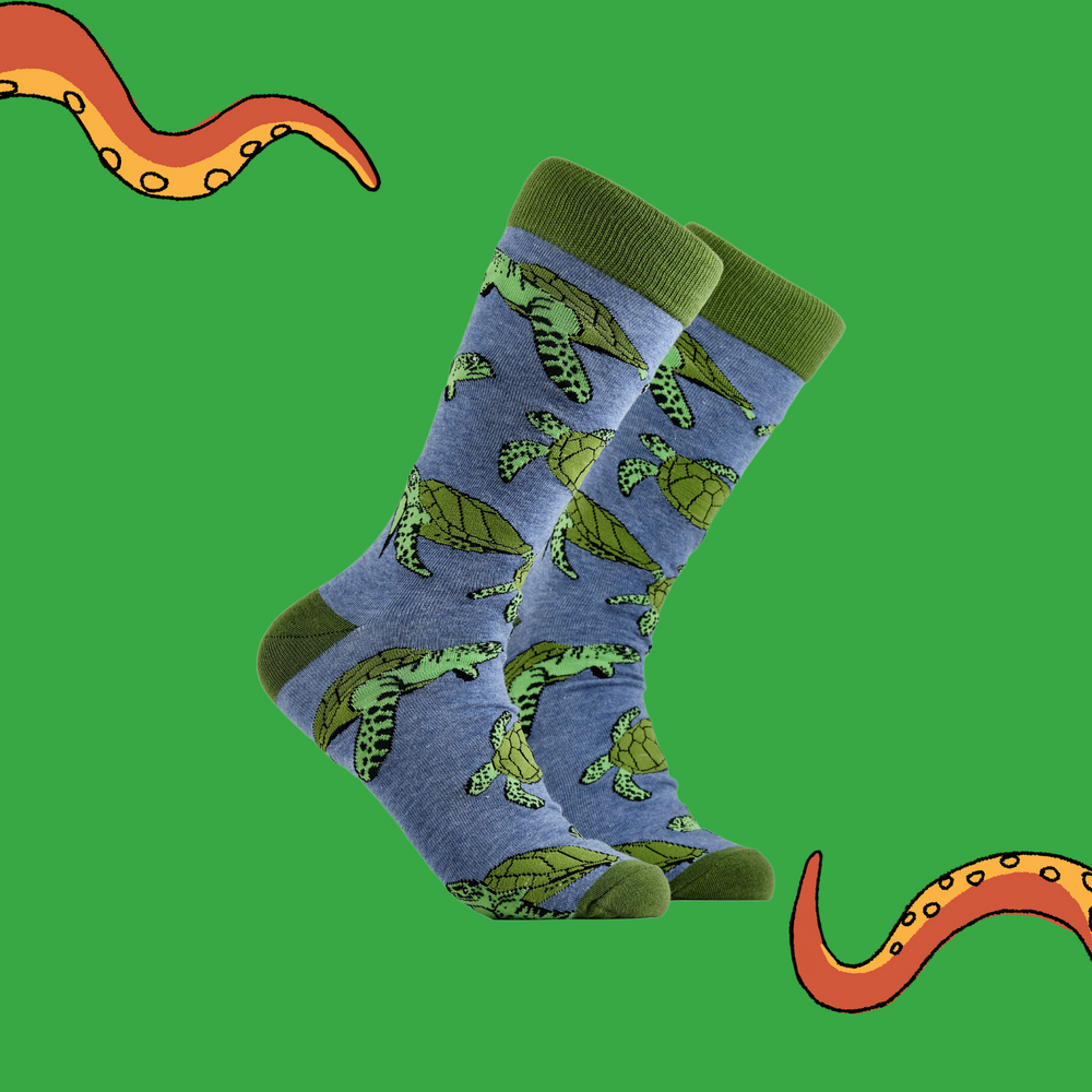 A pair of socks depicting sea turtles. Blue legs, green cuff, heel and toe.