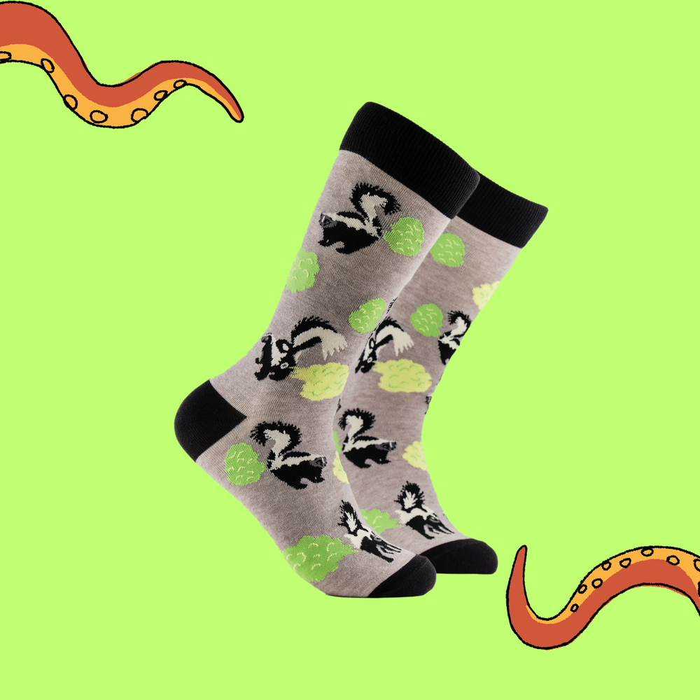 A pair of socks depicting stinky skunks. Grey legs, black cuff, heel and toe.