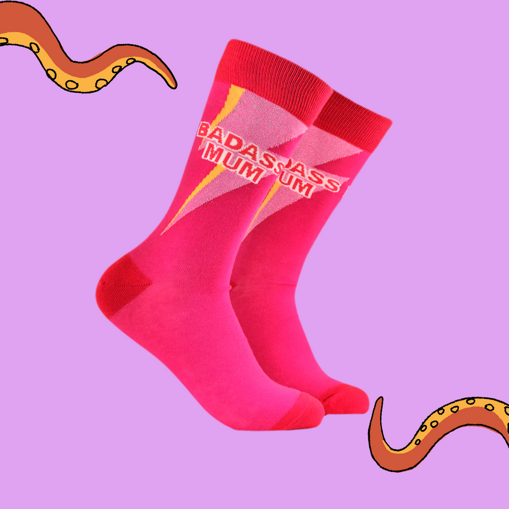 A pair of socks with he slogan Badass Mum. Pink legs, red heel, toe and cuff. 