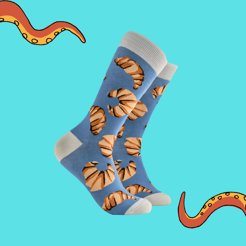 A pair of socks with a croissant motif. Blue legs, grey heel, toe and cuff. 