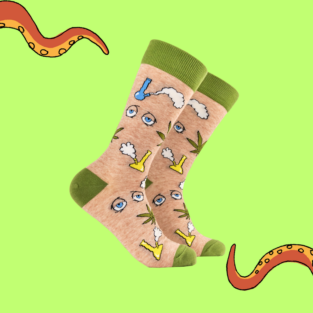 A pair of socks featuring bongs and weed. Beige legs, green heel, toe and cuff. 