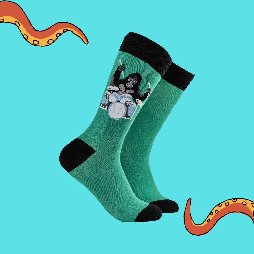 
                      
                        A pair of socks featuring a drumming gorilla. Green legs, black heel, toe and cuff. 
                      
                    