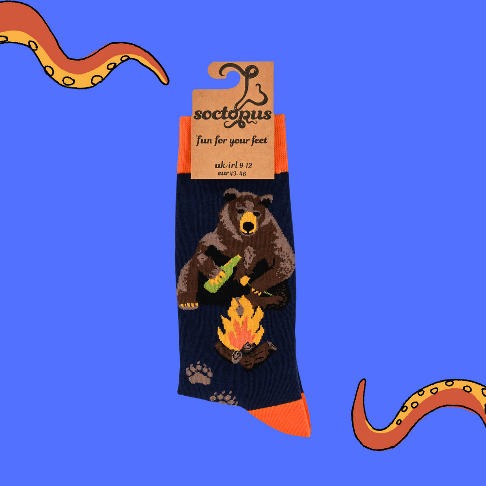 
                      
                        A pair of socks depicting a bear sitting by a campfire. Dark blue legs, orange cuff, heel and toe. 
                      
                    