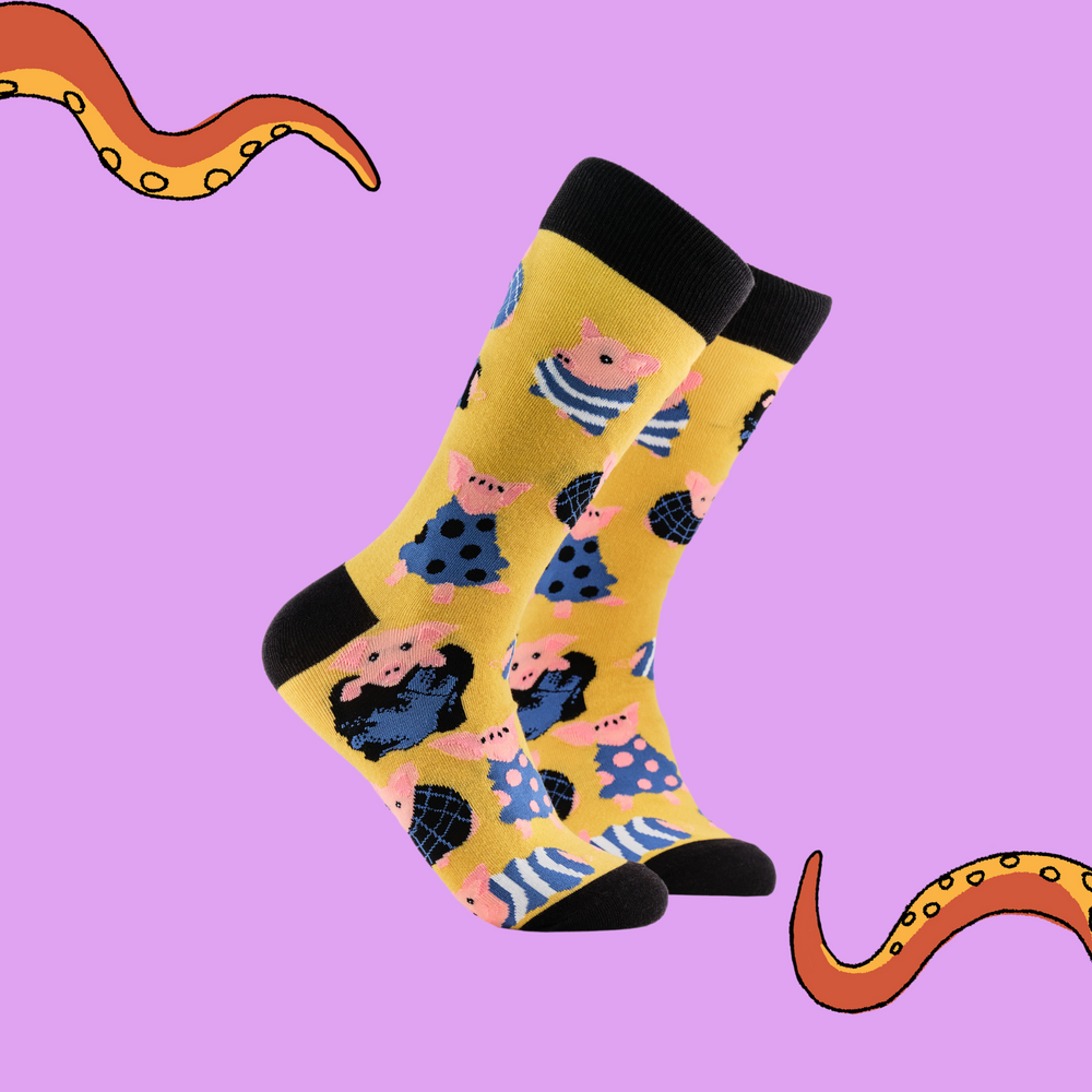 
                      
                        A pair of socks depicting Pigs wrapped up in cosy blankets. Yellow legs, black cuff, heel and toe.
                      
                    