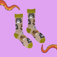 A pair of socks depicting various grumpy cats. Light brown legs, green cuff, heel and toe.