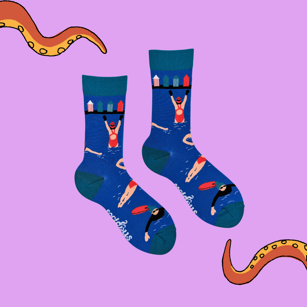 
                  
                    A pair of socks depicting swimmers and beach huts. Blue legs, light blue cuff, heel and toe.
                  
                