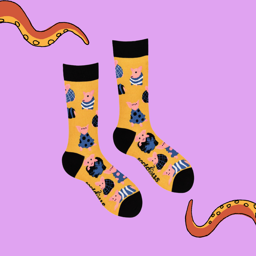 
                      
                        A pair of socks depicting Pigs wrapped up in cosy blankets. Yellow legs, black cuff, heel and toe.
                      
                    