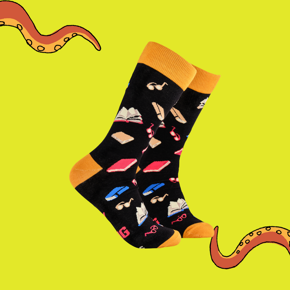 
                      
                        A pair of socks depicting books and reading glasses. Black legs, yellow cuff, heel and toe.
                      
                    