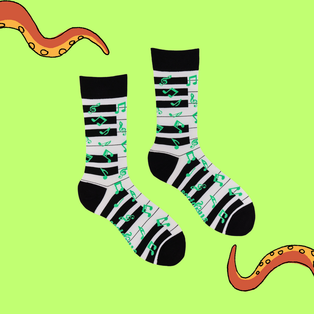 
                      
                        A pair of socks depicting a piano keyboard and green music notes. Black and white piano legs, black cuff, heel and toe.
                      
                    