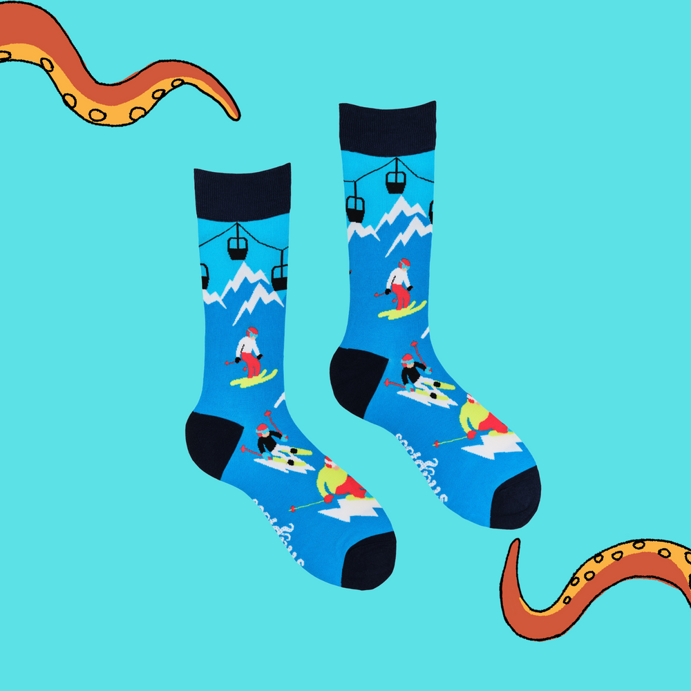 
                  
                    A pair of socks depicting skiers on the slopes. Blue legs, dark blue cuff, heel and toe.
                  
                