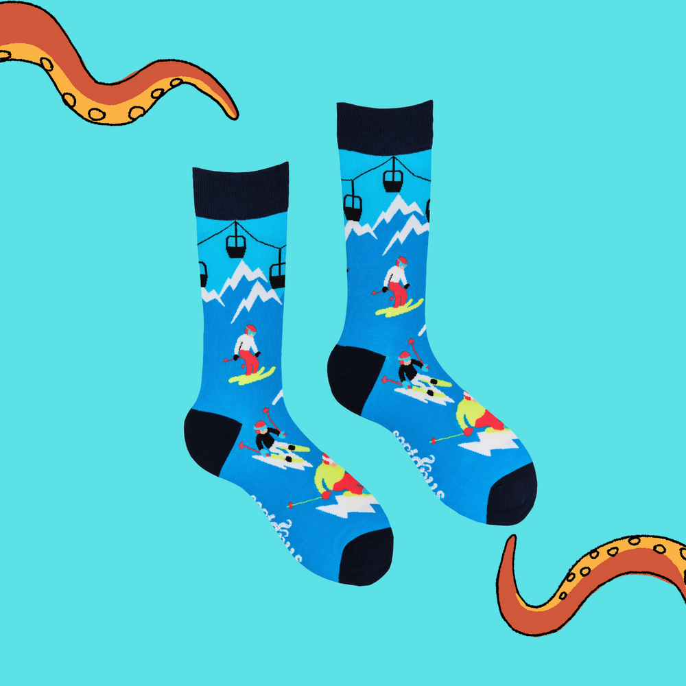 
                      
                        A pair of socks depicting skiers on the slopes. Blue legs, dark blue cuff, heel and toe.
                      
                    