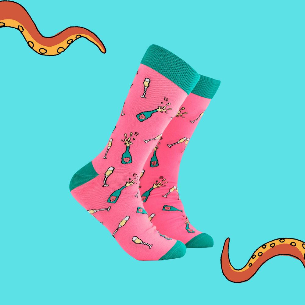 A pair of socks depicting champagne bottles and glasses. Pink legs, turquoise cuff, heel and toe.