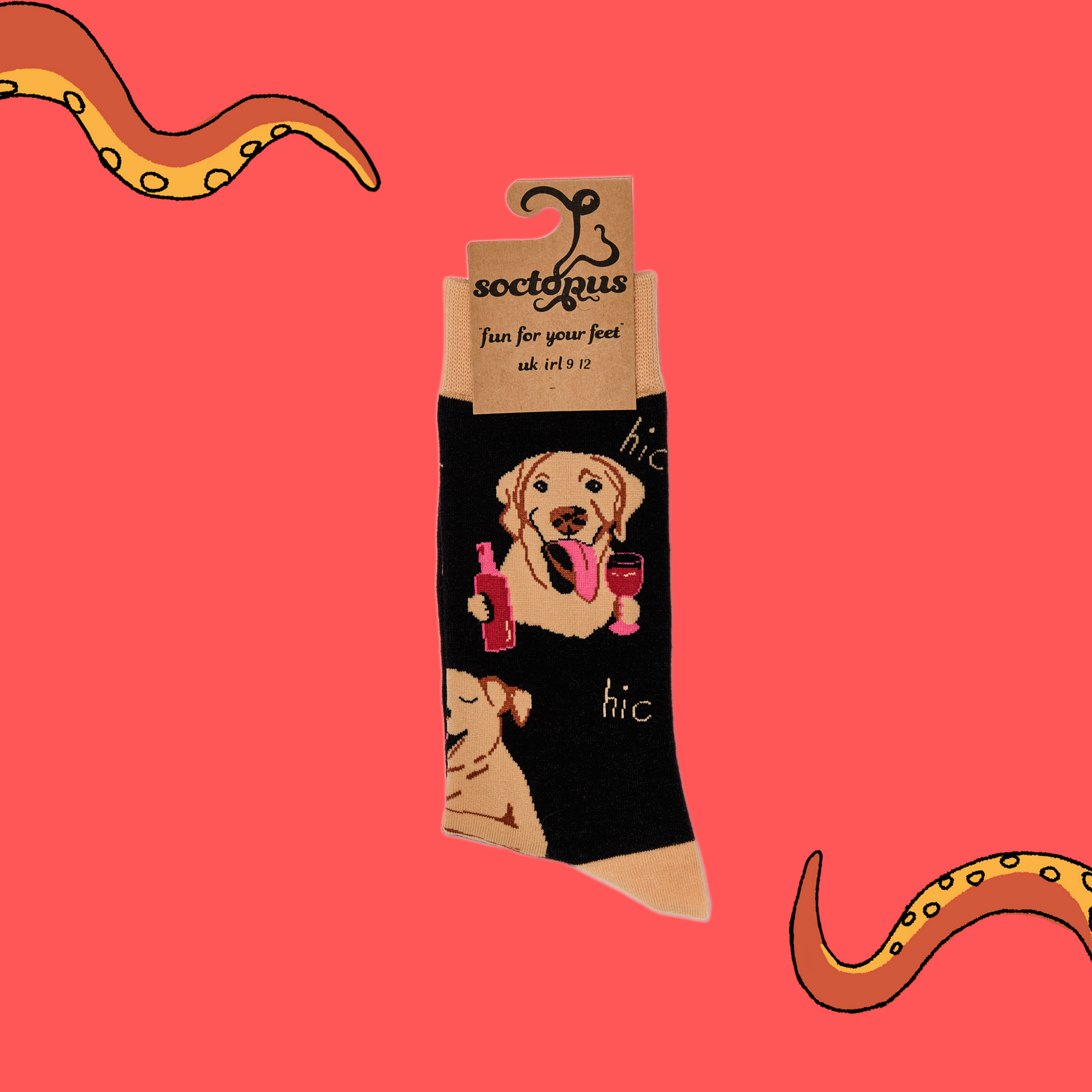 A pair of socks depicting labs drinking wine. Black legs, light brown cuff, heel and toe. In Soctopus Packaging.