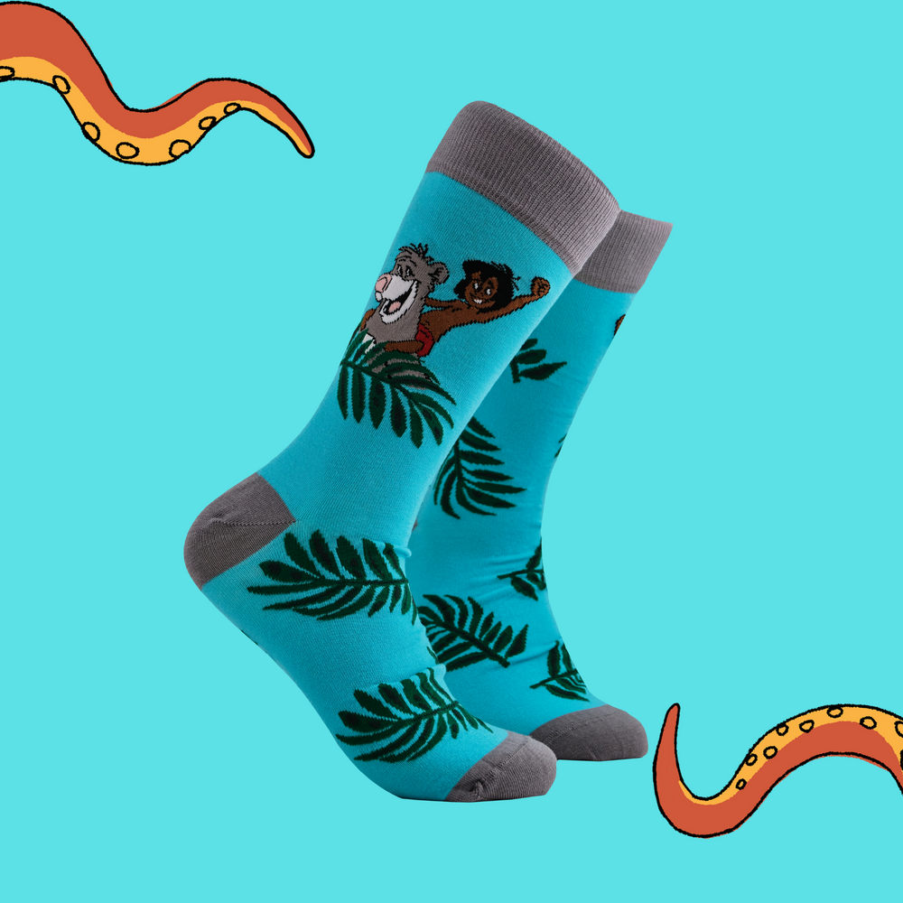 
                      
                        A pair of socks depicting Mowglie and Baloo playing in the jungle. Turquoise legs, grey toes, heel and cuff.
                      
                    