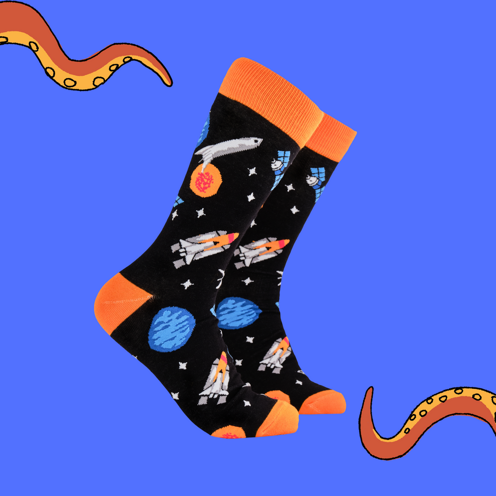 A pair of socks depicting space craft in space. Black legs, orange cuff, heel and toe.