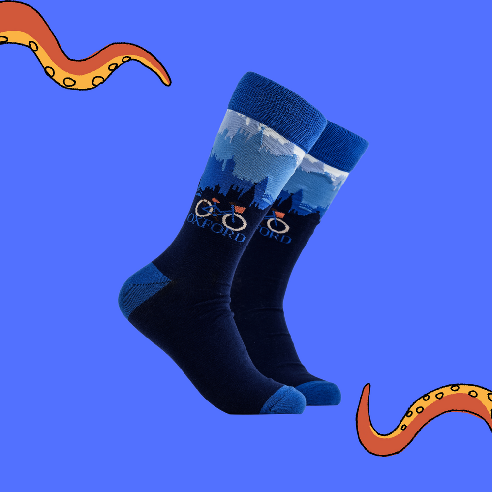 A pair of socks depicting the Oxford skyline and a traditional bicycle. Blue legs, blue cuff, heel and toe.