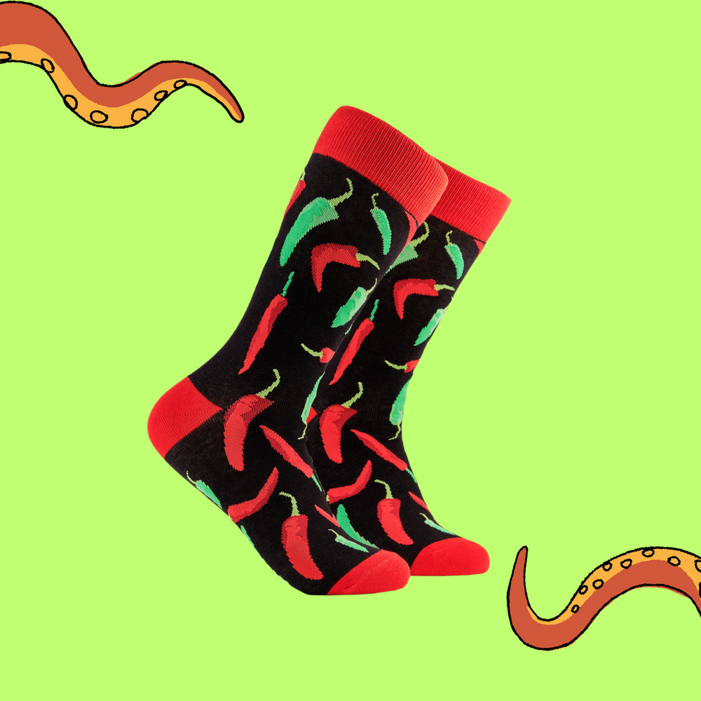 A pair of socks depicting red and green chilli peppers.. Black legs, red cuff, heel and toe.